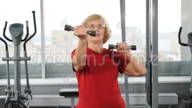 活跃的老年退休妇女带着杠铃在健身房。 主动快乐的晚年理念.. 积极的退休人员